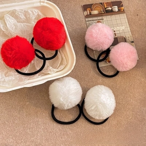 Detailed view of fluffy plush hair ties in red, pink, and white with black elastic bands