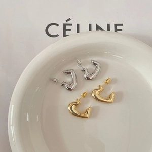 Detailed macro shot of glossy gold and silver minimalist heart-shaped stud earrings