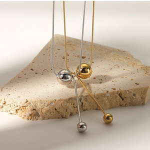 Close-up of spherical pendant necklaces in gold and silver finish on stone display