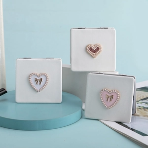 Detailed view of portable square PU leather makeup mirrors with pearl heart and bow accents