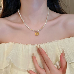 Elegant pearl choker necklace with gold blessing bag pendant on female neck
