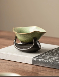 Macro detail of a vintage kiln-fired ceramic tea strainer with a green glaze on a stand