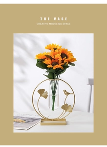 Creative gold metal ginkgo leaf bird vase with glass tube and sunflower on a white table