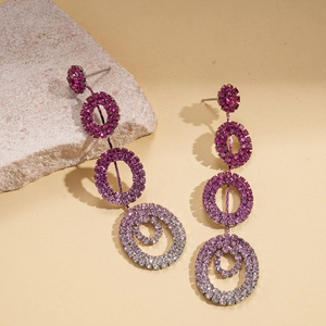 Macro view of long drop earrings with gradient purple rhinestones on a stone prop