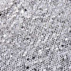 Gros plan de paillettes argentées cousues sur tissu maille de la robe dos nu