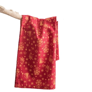 Serviette de Noël rouge avec motifs flocons dorés suspendue sur une branche rustique
