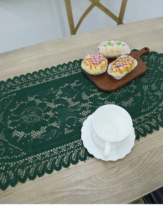 Detail of dark green lace table runner with intricate hollow-out weaving on wood