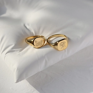 Macro detail of 18K gold-plated titanium rings with engraved butterfly and floral patterns