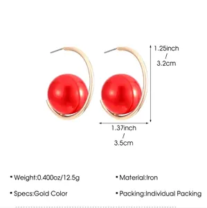 Detail view of gold C-shape hoop earrings with large red pearls and size dimensions