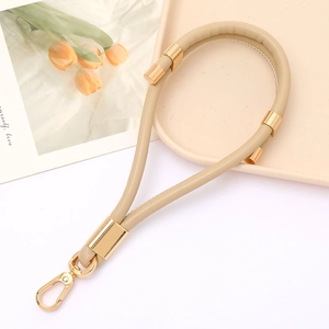 Detail of beige leather strap with polished gold metal lobster clasp and decorative rings