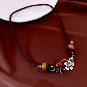 Vintage tiger eye stone necklace with red strawberry charm on elegant silk backdrop