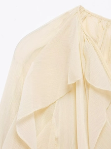 Detail of light yellow chiffon blouse featuring layered ruffles and pleated texture