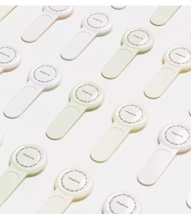 Close-up of minimalist toilet lid lifter in white, green, and pink pastel colors