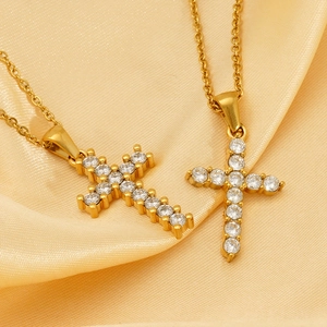 Close-up of gold cross necklaces with white zircon stones on champagne silk background