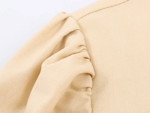 Detailed macro view of khaki puffed sleeve stitching on embroidered woven dress