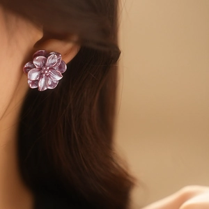 Gros plan d'une boucle d'oreille fleur en résine violette portée par un mannequin