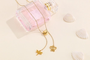 Détail du collier en Y en titane doré avec perle cœur et breloques libellule et papillon