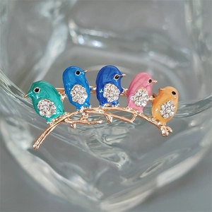 Macro shot of colorful enamel bird brooch with rhinestones perched on a twig