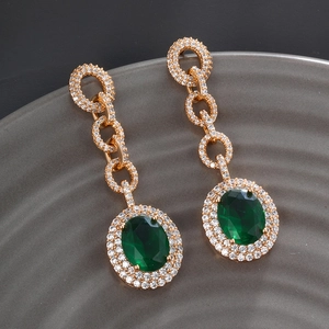 Detail of vintage emerald green earrings with full diamond pavé on a grey ceramic tray