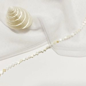 Polished white mother-of-pearl four-leaf clover charms on a strand for jewelry making