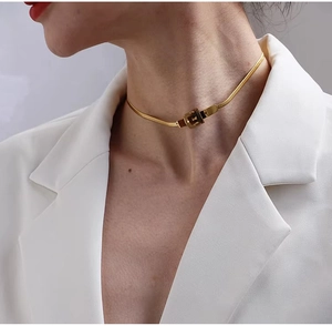 Detail of a minimalist gold buckle choker necklace on a white suit model