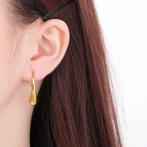 Close-up of a polished gold teardrop earring featuring a sleek curved metal design