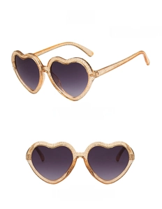 Detail view of heart-shaped kids sunglasses in translucent amber with gold glitter