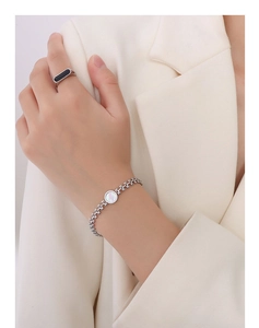 Close-up of silver chain bracelet with white shell inlay and sleek black enamel ring