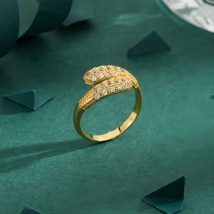 Minimalist gold snake ring with sparkling gemstones on a dark green background
