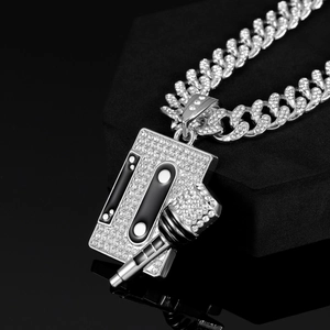 Close-up of silver-toned cassette tape and microphone pendant with shiny rhinestones