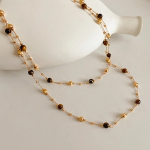 Detailed shot of double-layer gold plated necklace with tiger eye beads and metal spheres