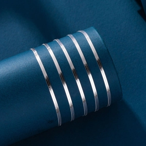 Macro detail of polished 925 sterling silver flat snake chain on dark blue background