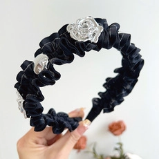 Detail of a black pleated velvet headband featuring silver metal rose floral charms