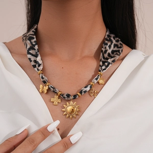 Detail of leopard print fabric necklace with gold sun and cross pendants on a model