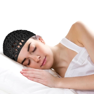 Detail of a handmade black crochet hairnet sleep cap worn by a model resting on a pillow