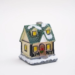 Luminous resin Christmas miniature snow house with green festive wreath on white background