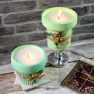 Close-up of lit high-waisted striped candle cups with dried flowers and twine accents