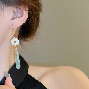 Close-up of elegant long teardrop earrings with white jade resin ring on model