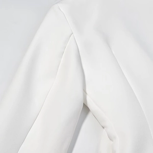 Detail of shoulder seam and tailoring on a white double-breasted blazer dress