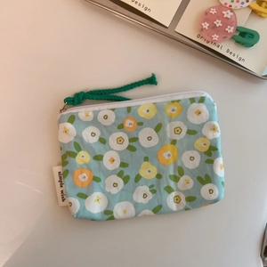 Close-up of small blue floral cotton coin purse with zipper and green woven rope pull