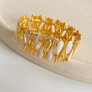 Detail view of vintage gold-plated teardrop bracelet with white enamel and rhinestones
