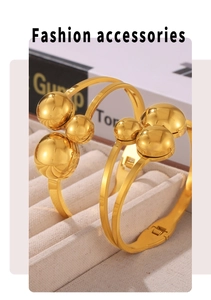 Detail of gold-plated stainless steel spring cuff bracelet with polished bead accents