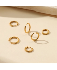 Detailed view of five graduated minimalist gold hoop earrings in polished steel