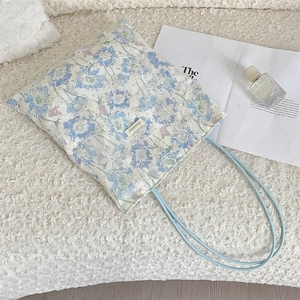 Detail of floral lace embroidery on white canvas tote bag with slim blue rope handles