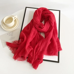 Red cotton linen scarf with raw edges and wrinkled texture elegantly styled on a desk