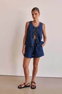 Detail of dark blue denim set with lace-up sleeveless vest and high-waisted wide shorts