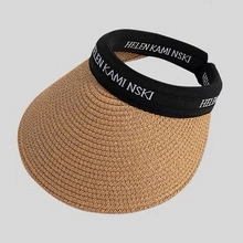 Macro detail of natural raffia straw weave and black logo elastic headband on a sun hat
