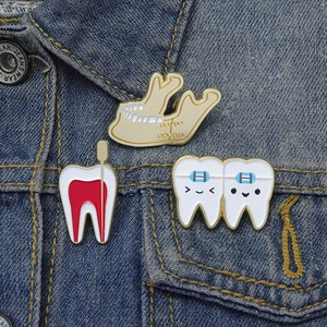Cartoon dental enamel pins on a blue denim jacket featuring tooth anatomy and jaw designs