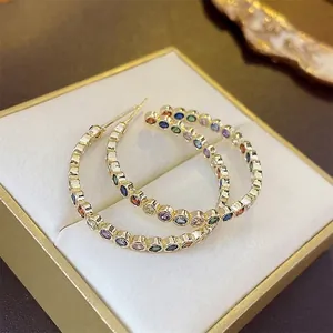 Luxurious gold C-shaped earrings with colorful pave zircon stones in a velvet gift box