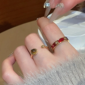 Detail of 18k gold plated tiger eye adjustable ring and red enamel band on fingers
